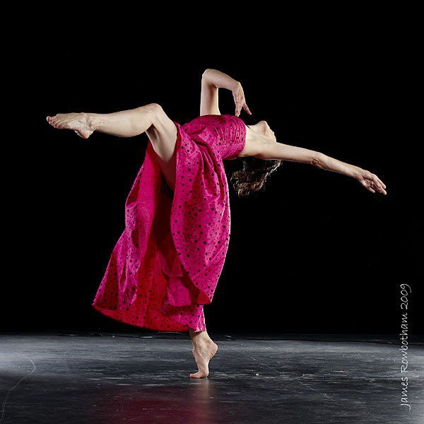 A woman in a pink dress is dancing on a stage