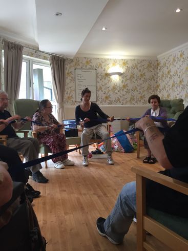 A group of people are sitting in chairs in a room playing with a rope.