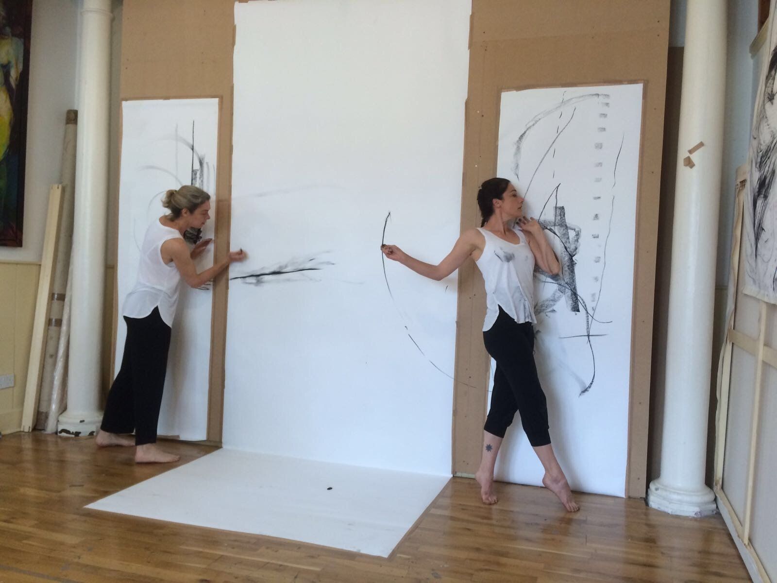 Two women are standing in front of a wall with drawings on it