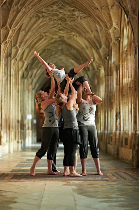 A group of people are standing in a hallway holding each other up in the air.