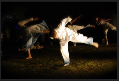 A man in a white shirt is doing a handstand in the dark