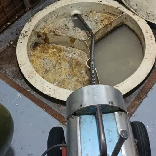 Un fontanero repara la tubería del lavabo mientras una mujer permanece de pie cerca en un baño.