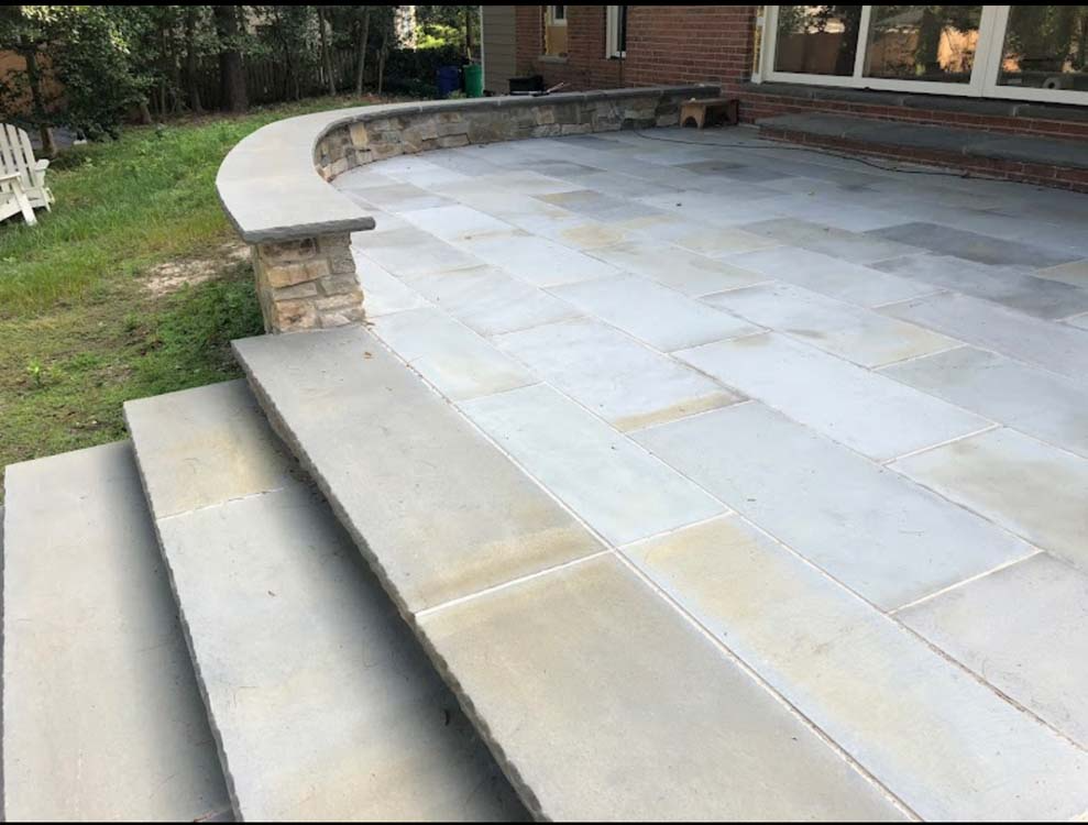 A patio with stairs leading up to it and a stone wall.