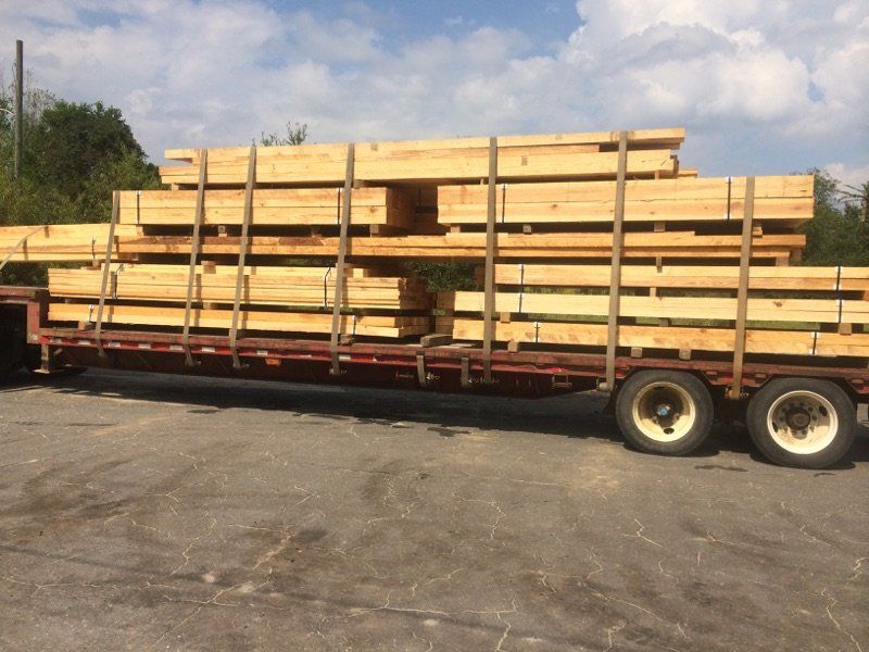 A truck is carrying a large stack of wooden beams