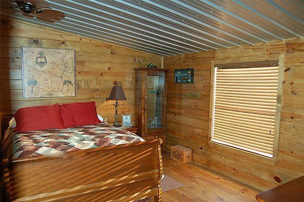 A bedroom in a log cabin with a bed and two windows.