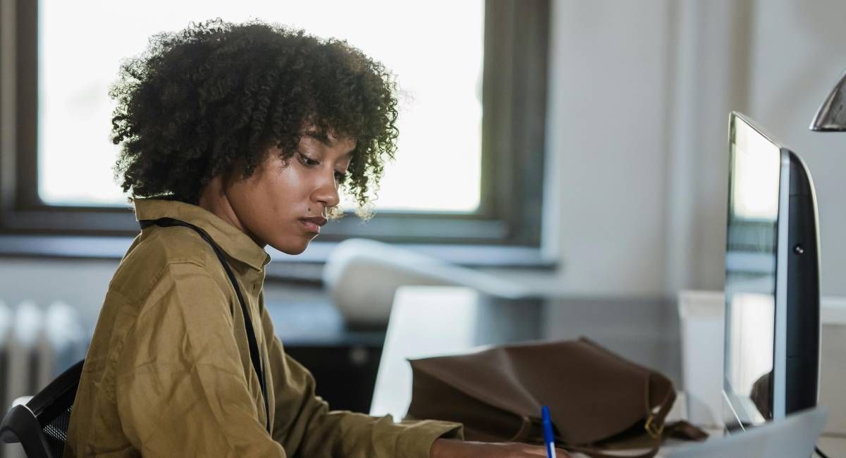 A woman sitting at her desk, checking data on a screen