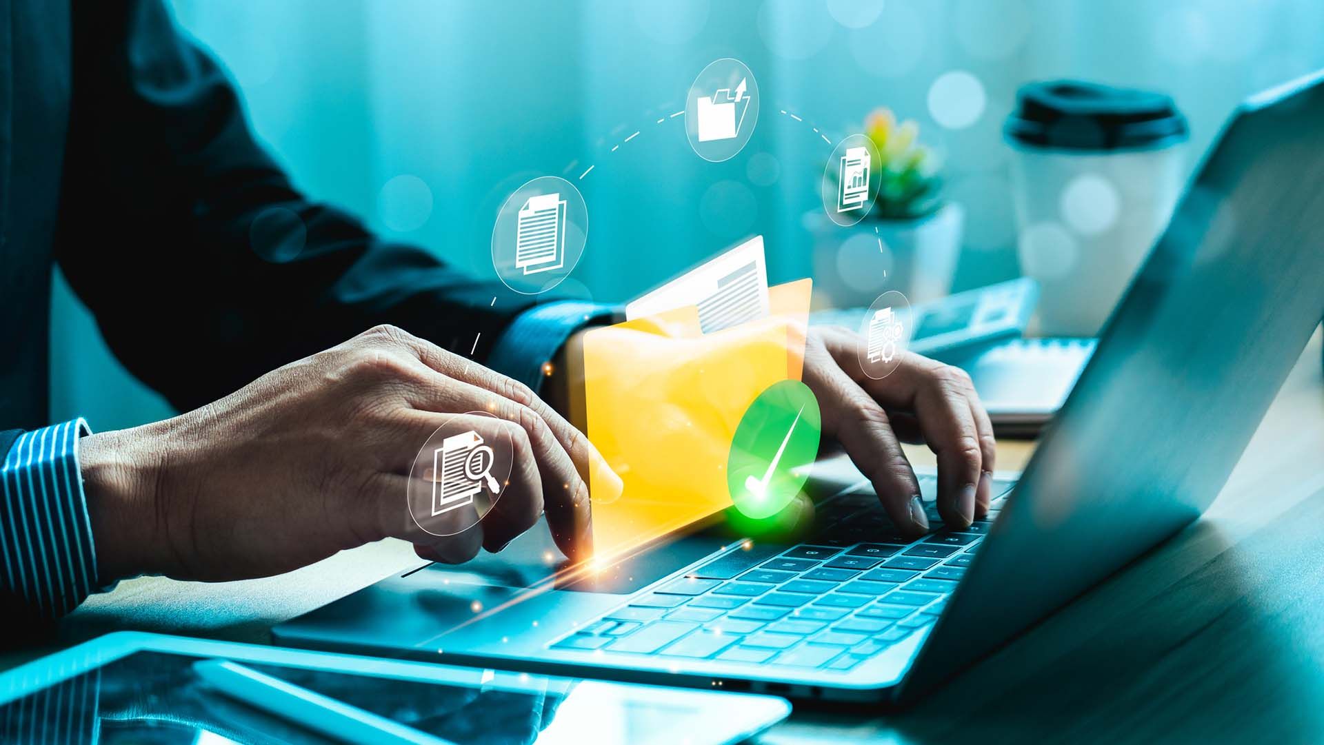 A man is typing on a laptop computer while holding a folder.