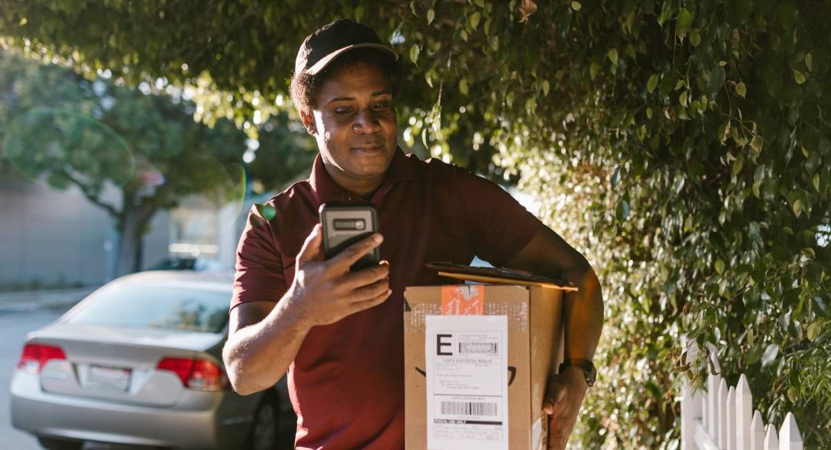 Courier delivering a parcel and checking his phoe ne