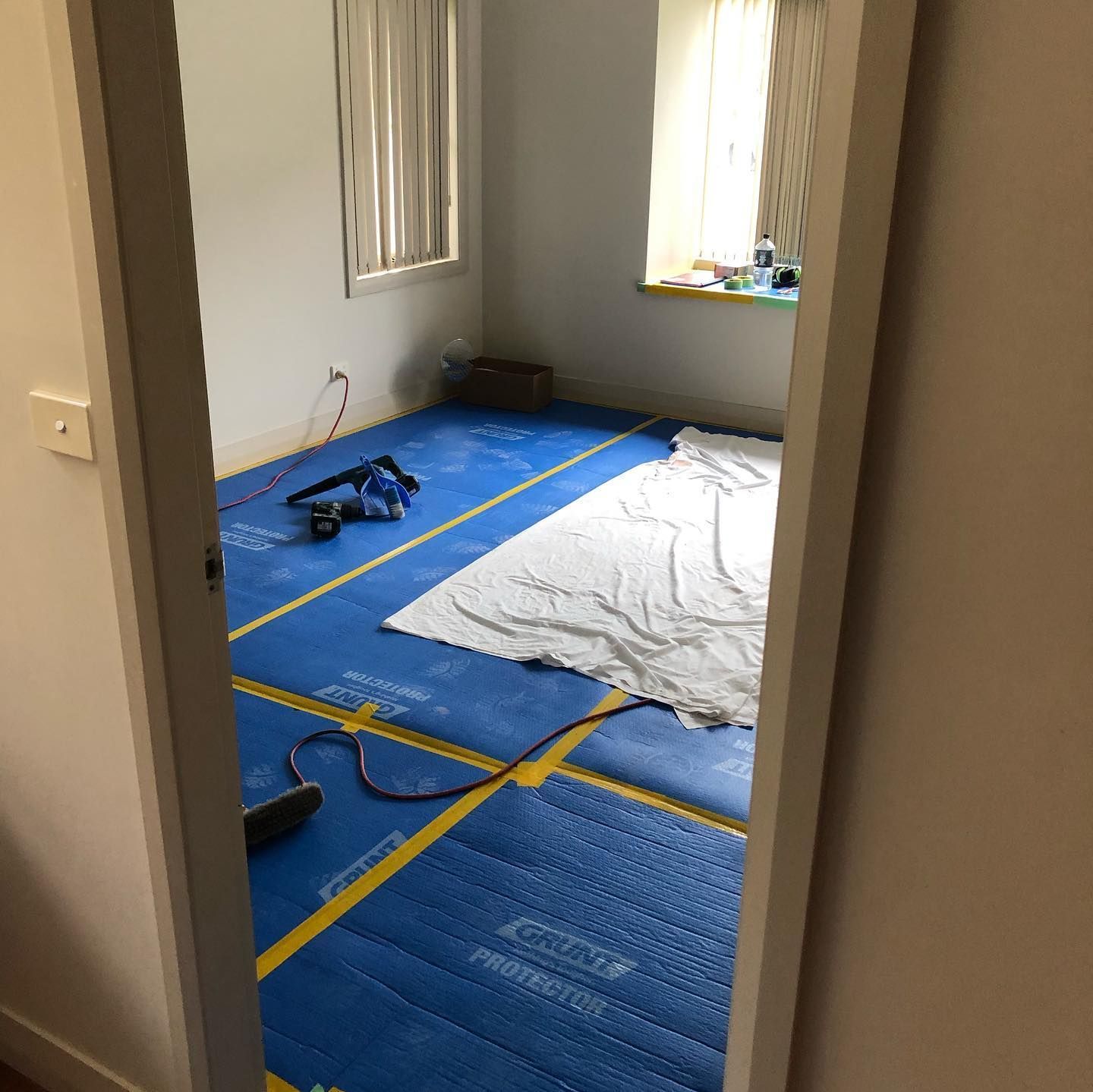 A Room With Blue and Yellow Flooring, White Walls, and Two Windows — JNR Building And Maintenance in Green Hill, QLD