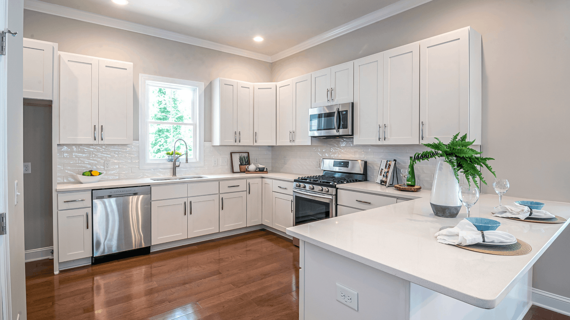 White kitchen with stainless steel appliances, white countertops, and wood floors — JNR Building And Maintenance in Green Hill, QLD