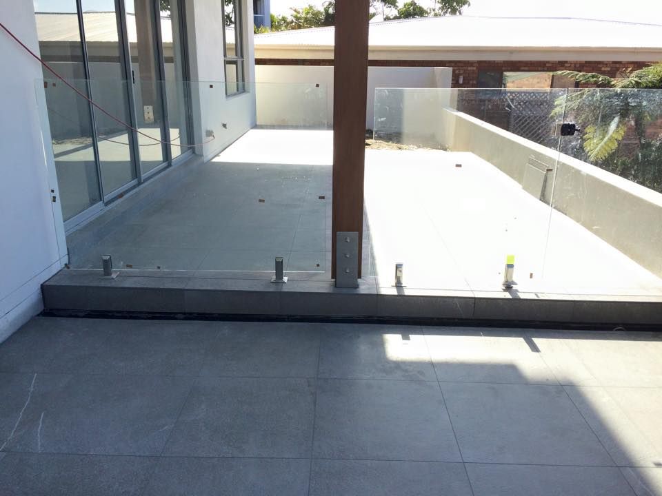 A Modern Patio With Glass Railings and Concrete Flooring — JNR Building And Maintenance in Green Hill, QLD