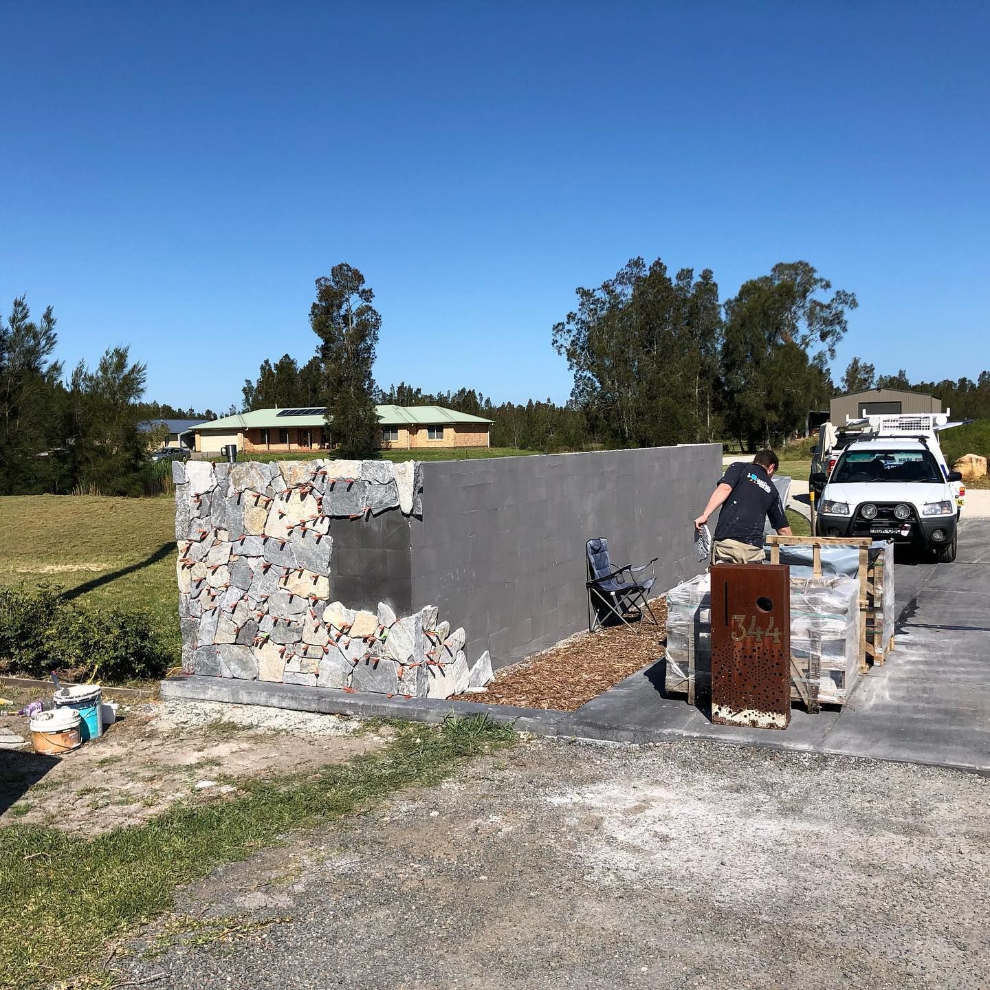 Man Working on Stone Wall, Next to Parked Truck — JNR Building And Maintenance in Green Hill, QLD