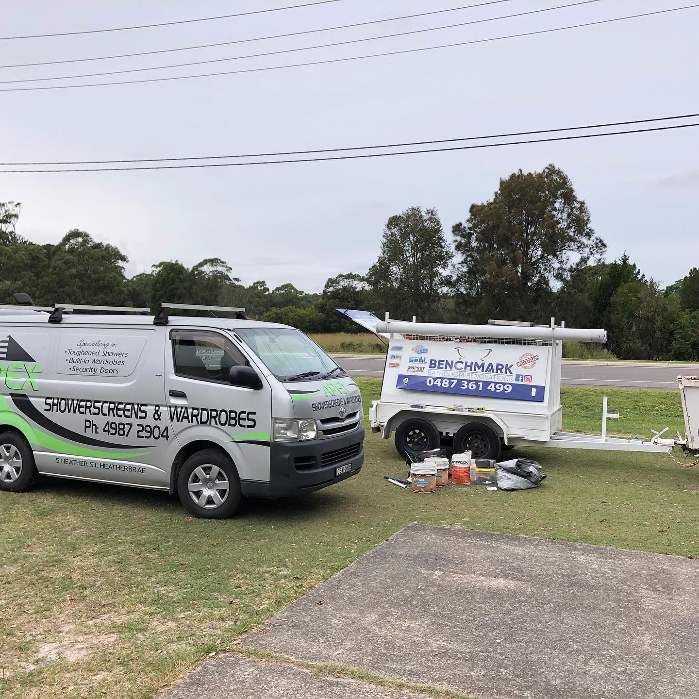 Van and Trailer Parked on Grass, Both Displaying Business Logos — JNR Building And Maintenance in Green Hill, QLD