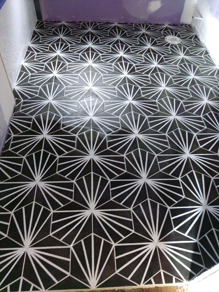 Bathroom floor featuring black and white geometric fan-patterned tiles in a repeating sunburst design.