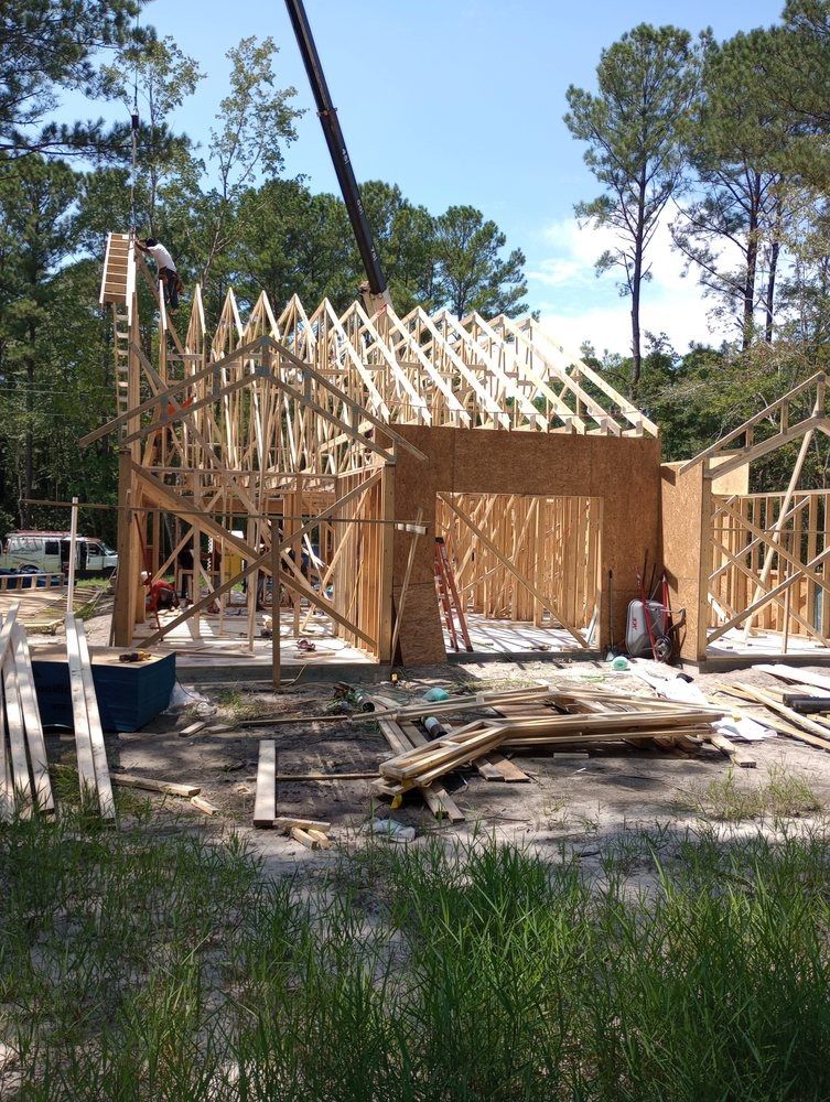 Construction workers framing the roof of a house under construction in a wooded area.
