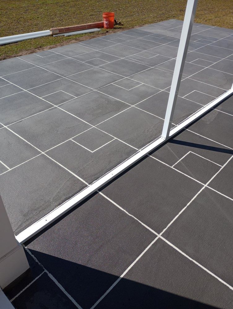 A patio surface with grey tiles featuring a white, painted grid pattern that creates a decorative design.