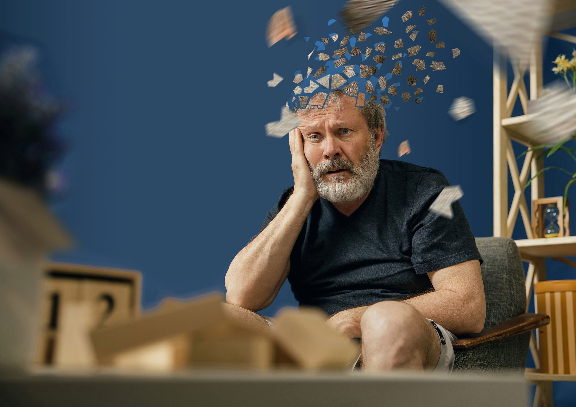 A man with a beard is sitting in a chair with his head in his hands.