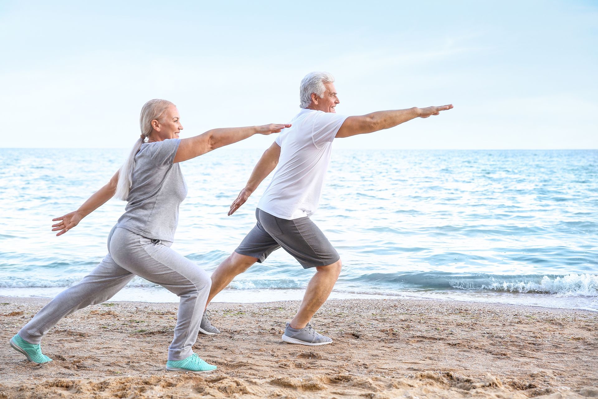 two seniors performing balance exercises in the beach