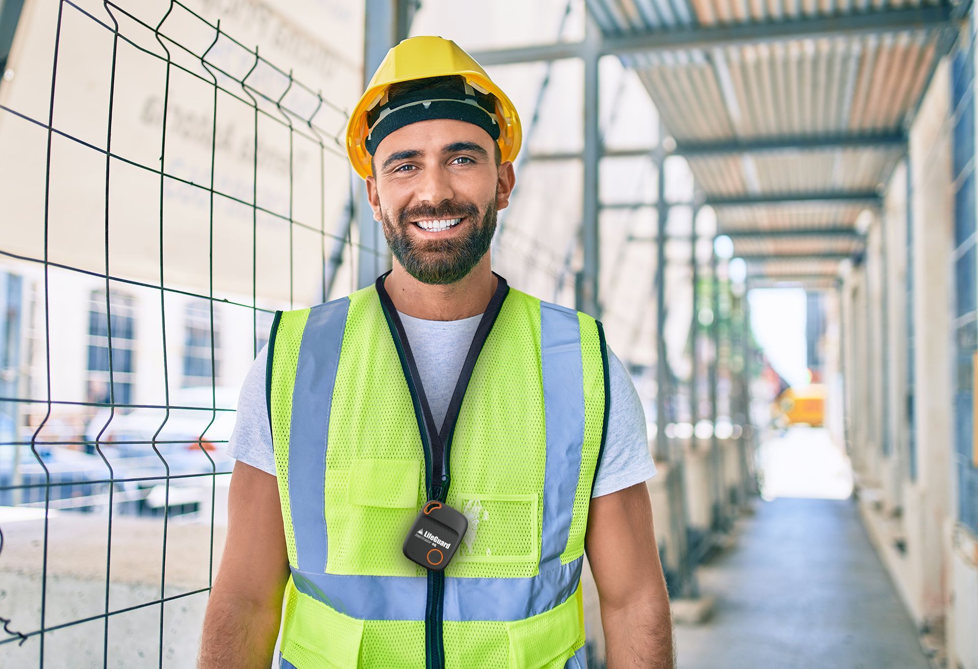 A construction worker wearing a hard hat and safety vest is smiling at the camera.
