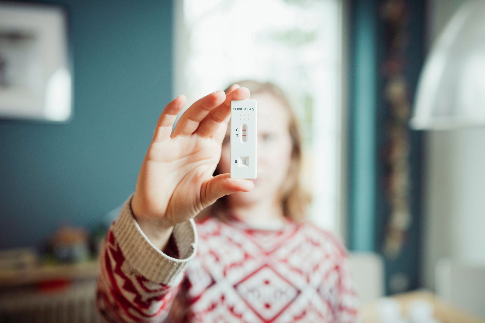 A woman is holding a pregnancy test in her hand.