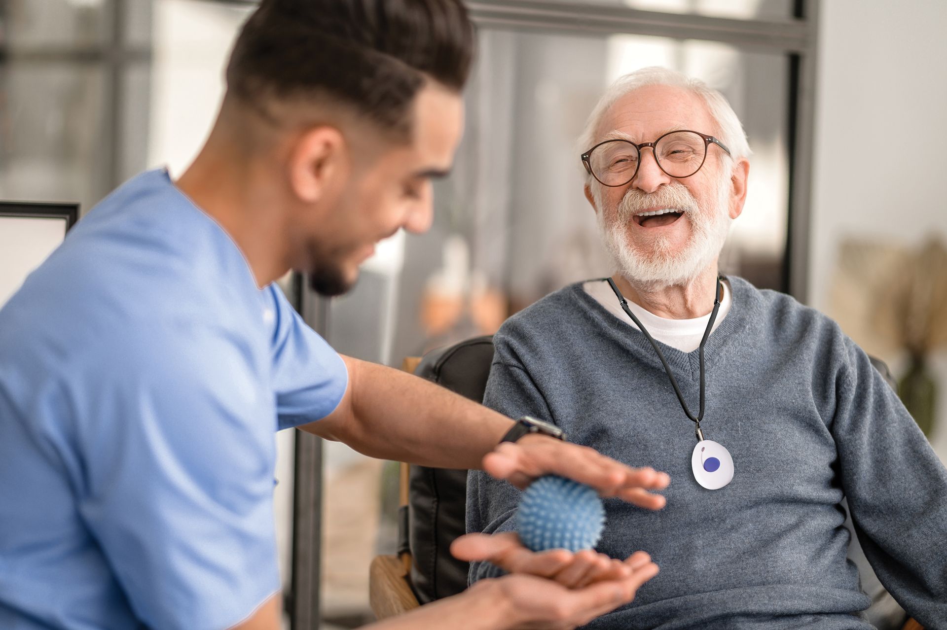 A nurse is helping an elderly man in a wheelchair with a ball.