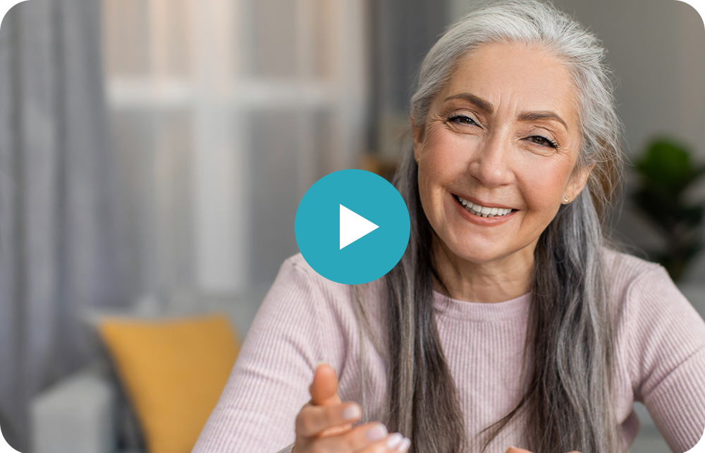 An elderly woman with gray hair is smiling and looking at the camera.