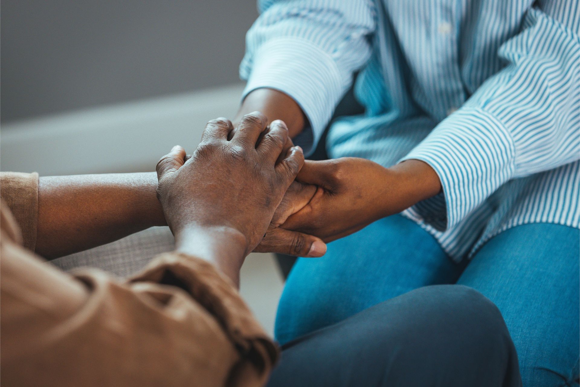 Two people are holding hands while sitting on a couch.