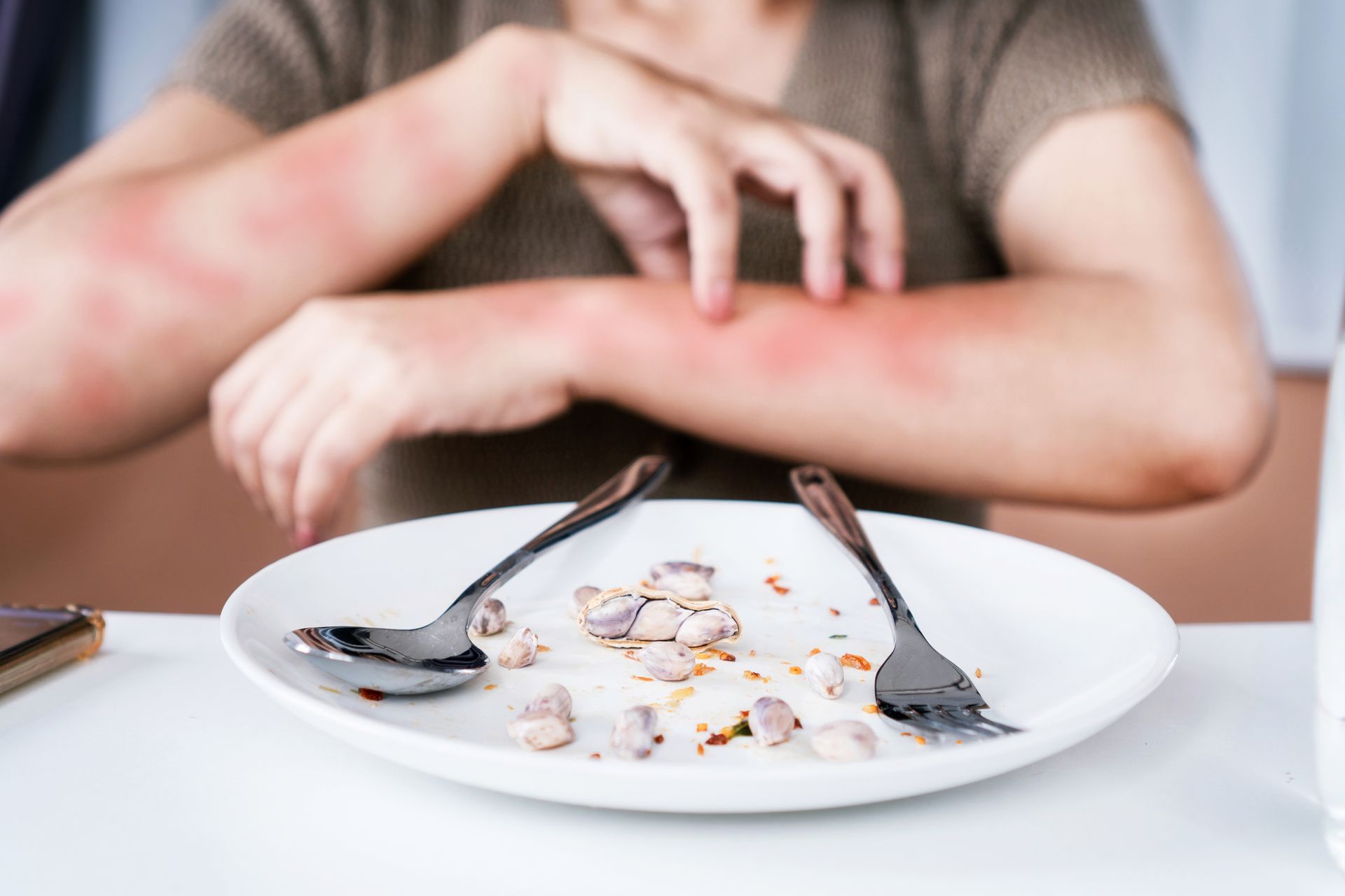 A woman is scratching her arm in front of a plate of food.