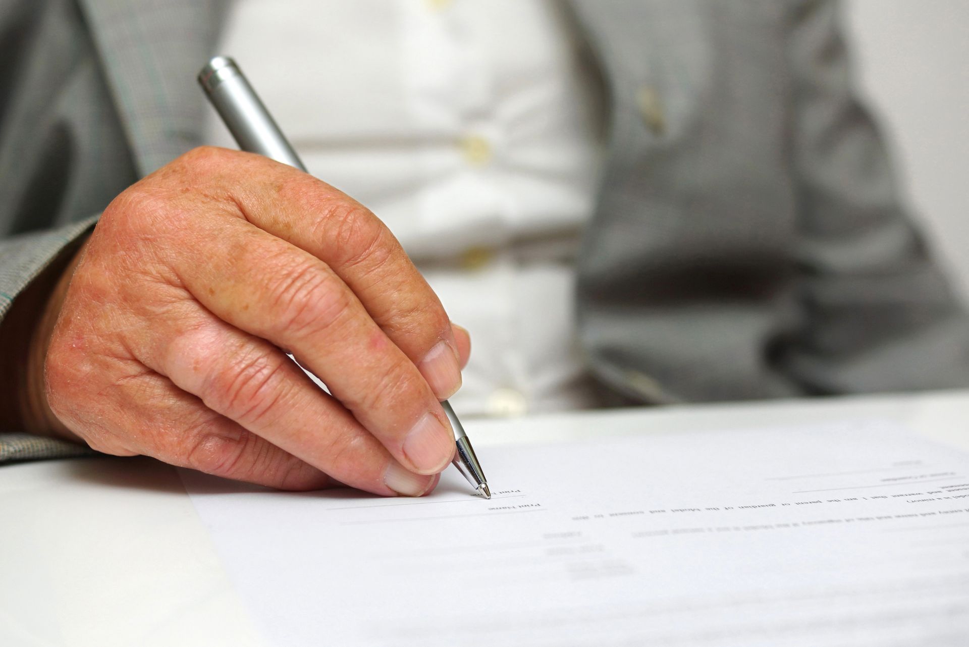 A man is writing on a piece of paper with a pen.