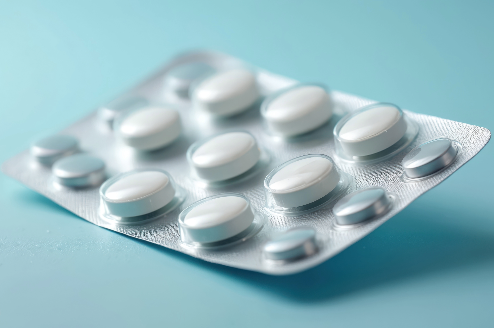 White pills in a silver blister pack on a blue surface.