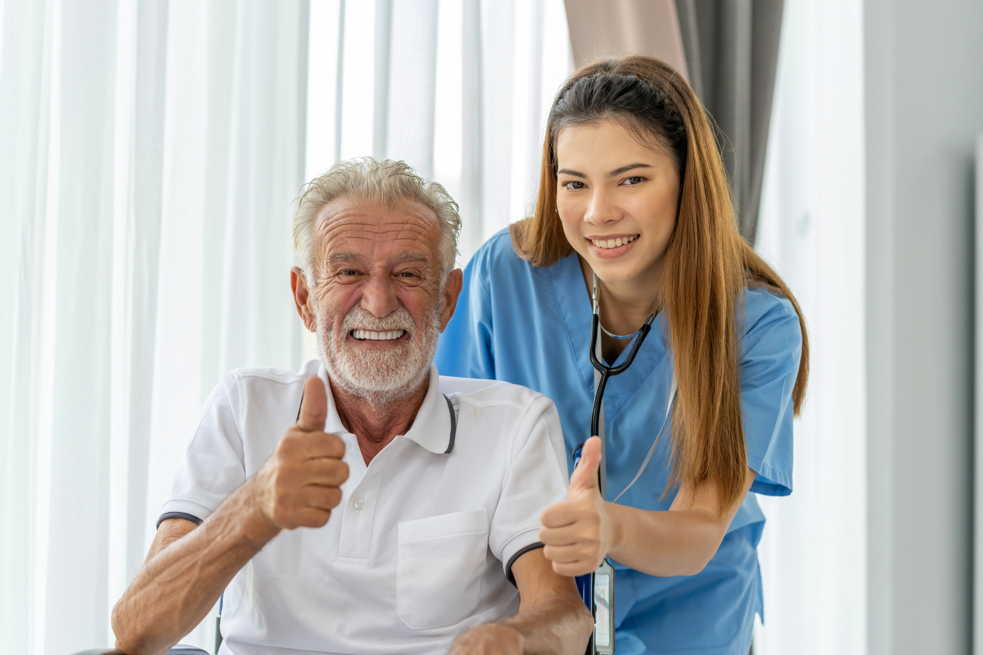 A nurse is helping an elderly man with a cane and giving him a thumbs up.