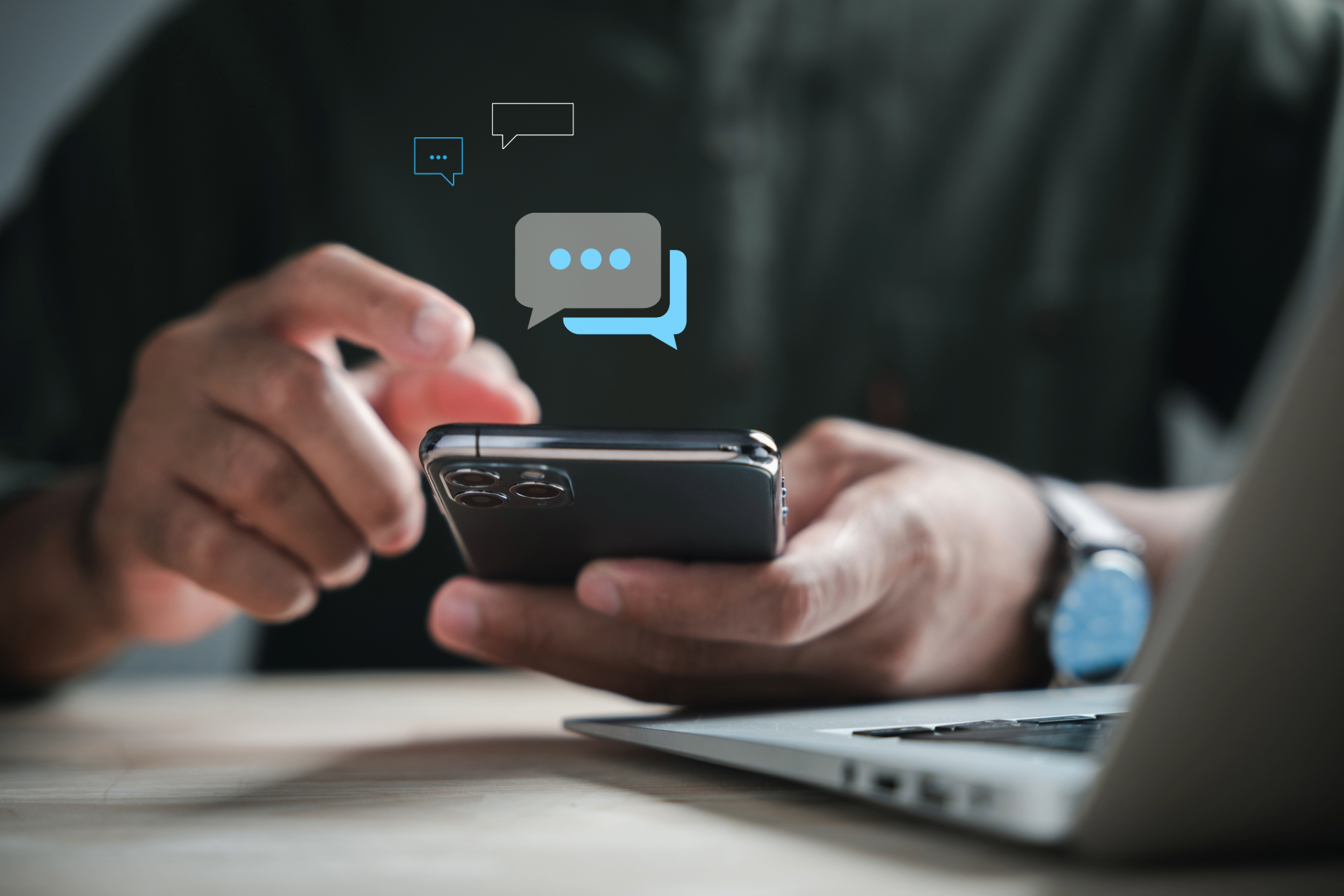 A man is sitting at a table using a cell phone.