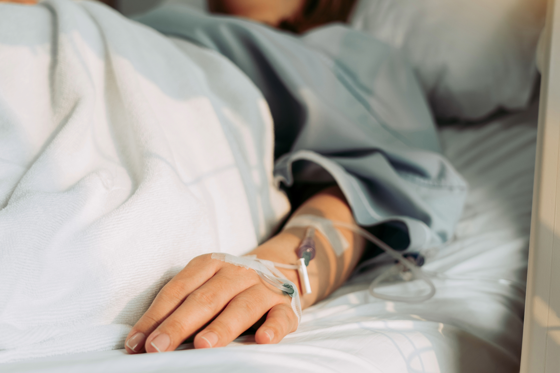A woman is laying in a hospital bed with an iv in her arm.