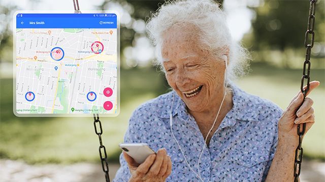 An elderly woman is sitting on a swing looking at her cell phone.