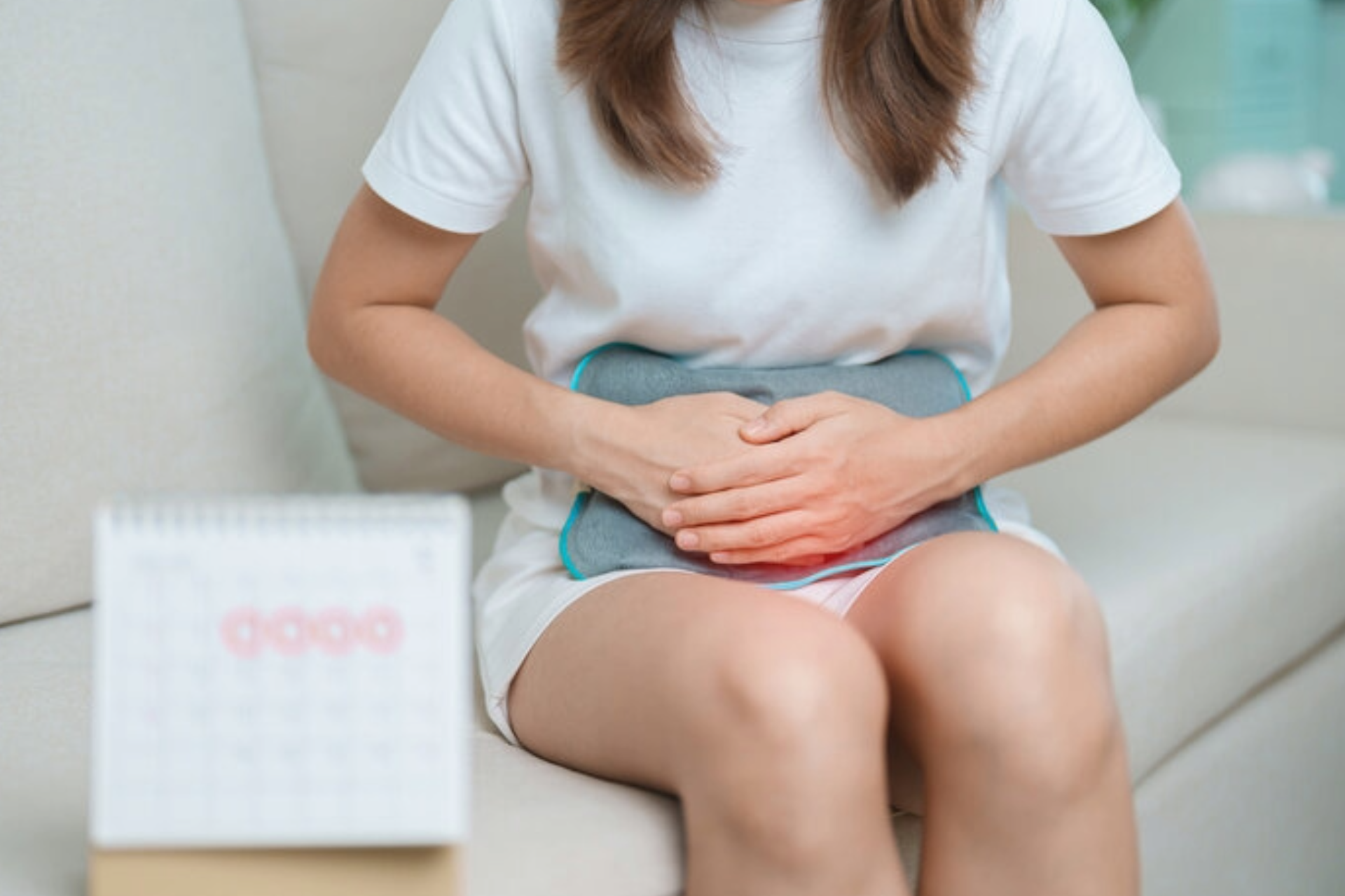 Female suffers from premenstrual ache and body health problem with a calendar on a table nearby.