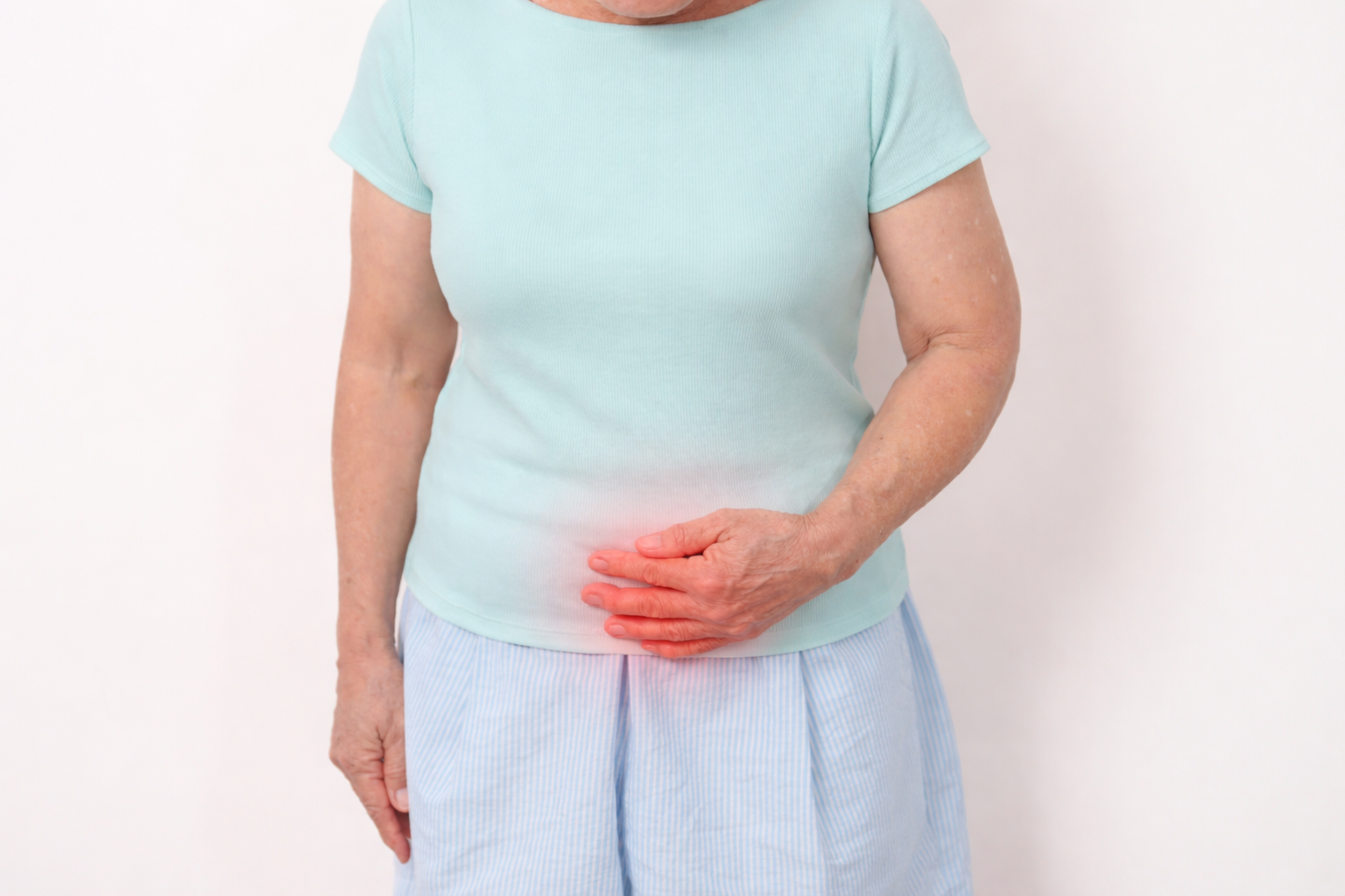 Person in a light blue shirt clutching their abdomen, which is highlighted in red to indicate pain.