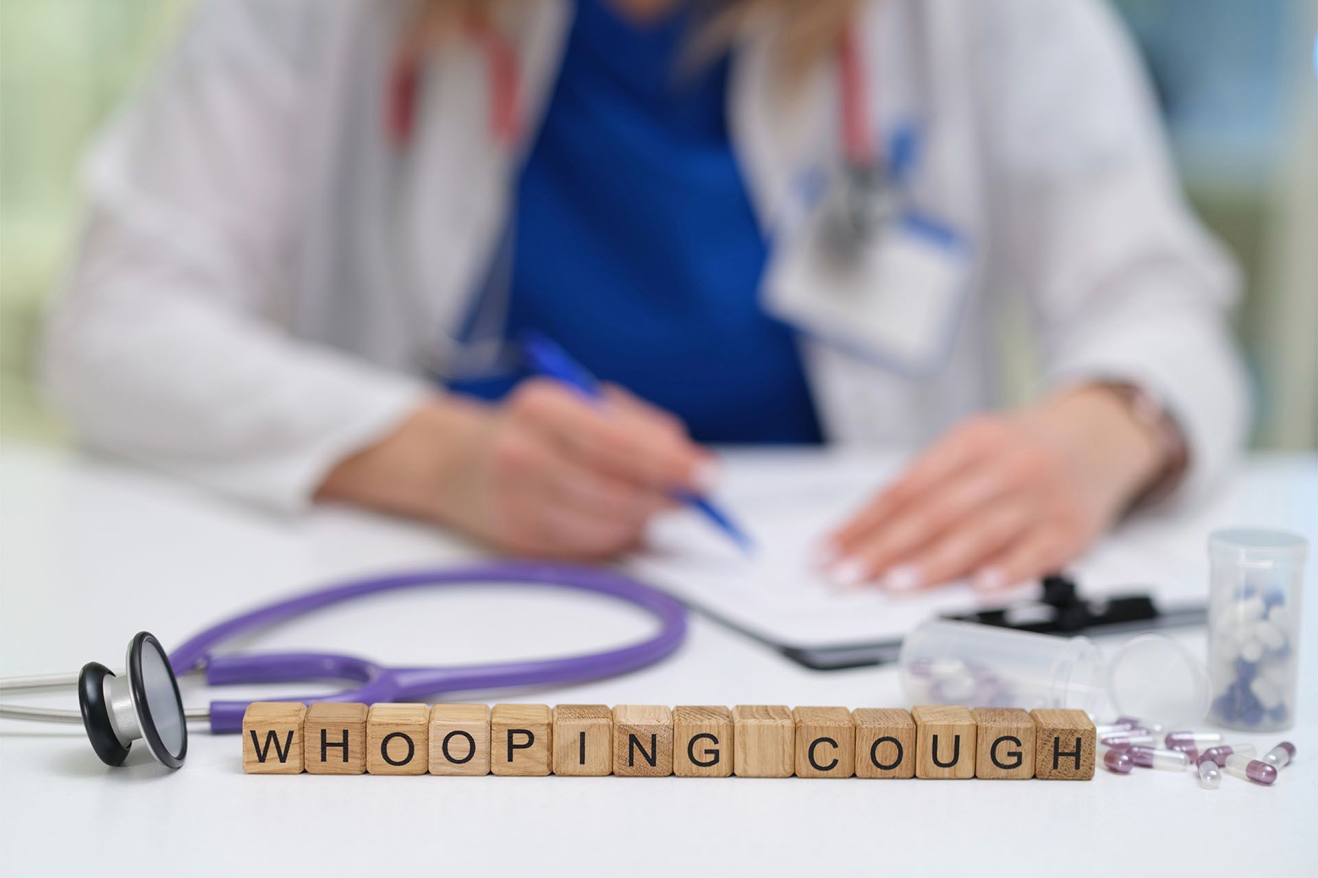 A doctor is sitting at a desk with a clipboard and a stethoscope.