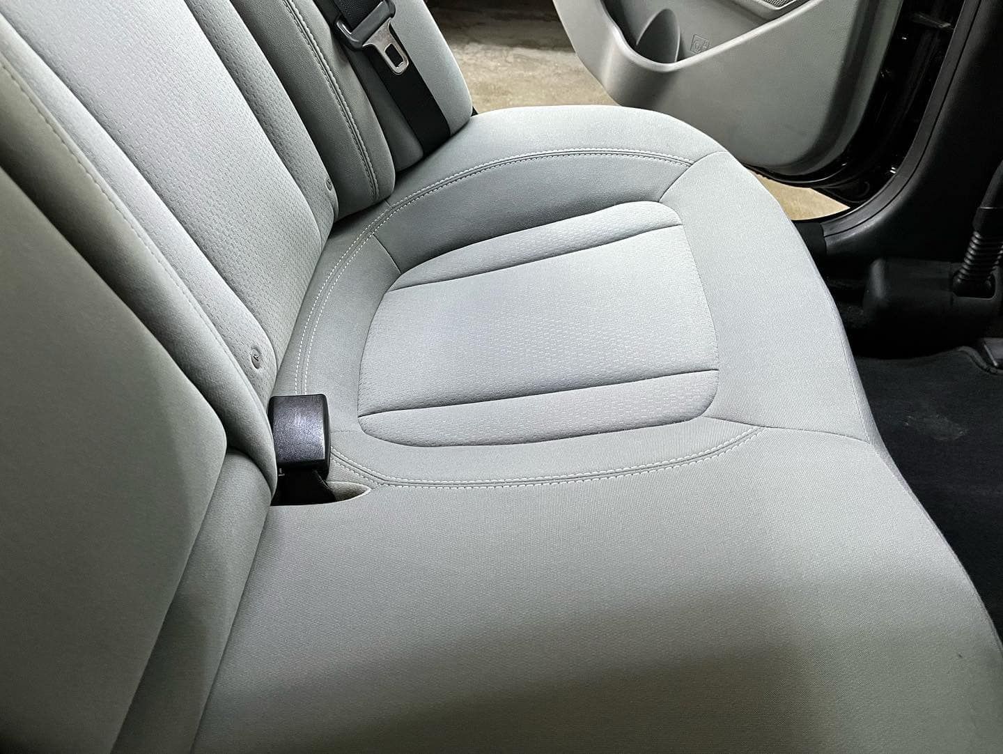 Light gray car backseat with a seat belt buckle, close-up.