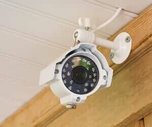 White security camera mounted on a wooden structure.