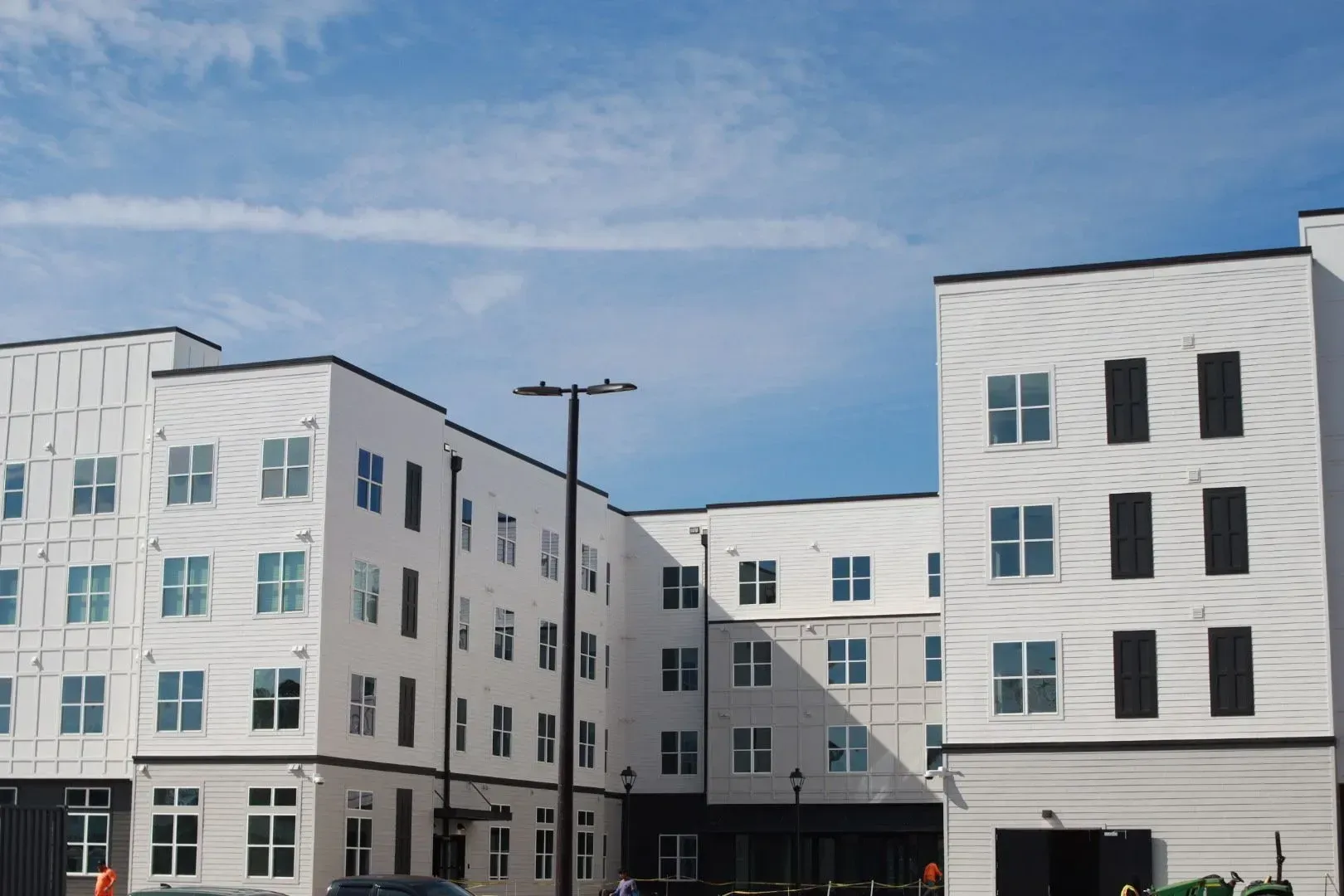 White modern apartment building exterior with multiple windows against a blue sky.