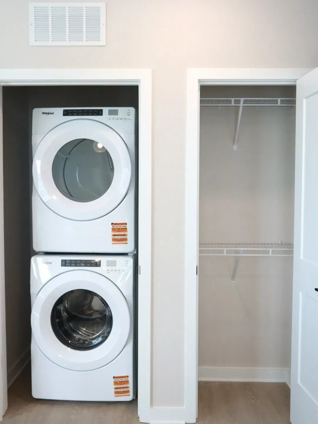 Stacked washer and dryer in a laundry closet next to an empty closet with wire shelving.
