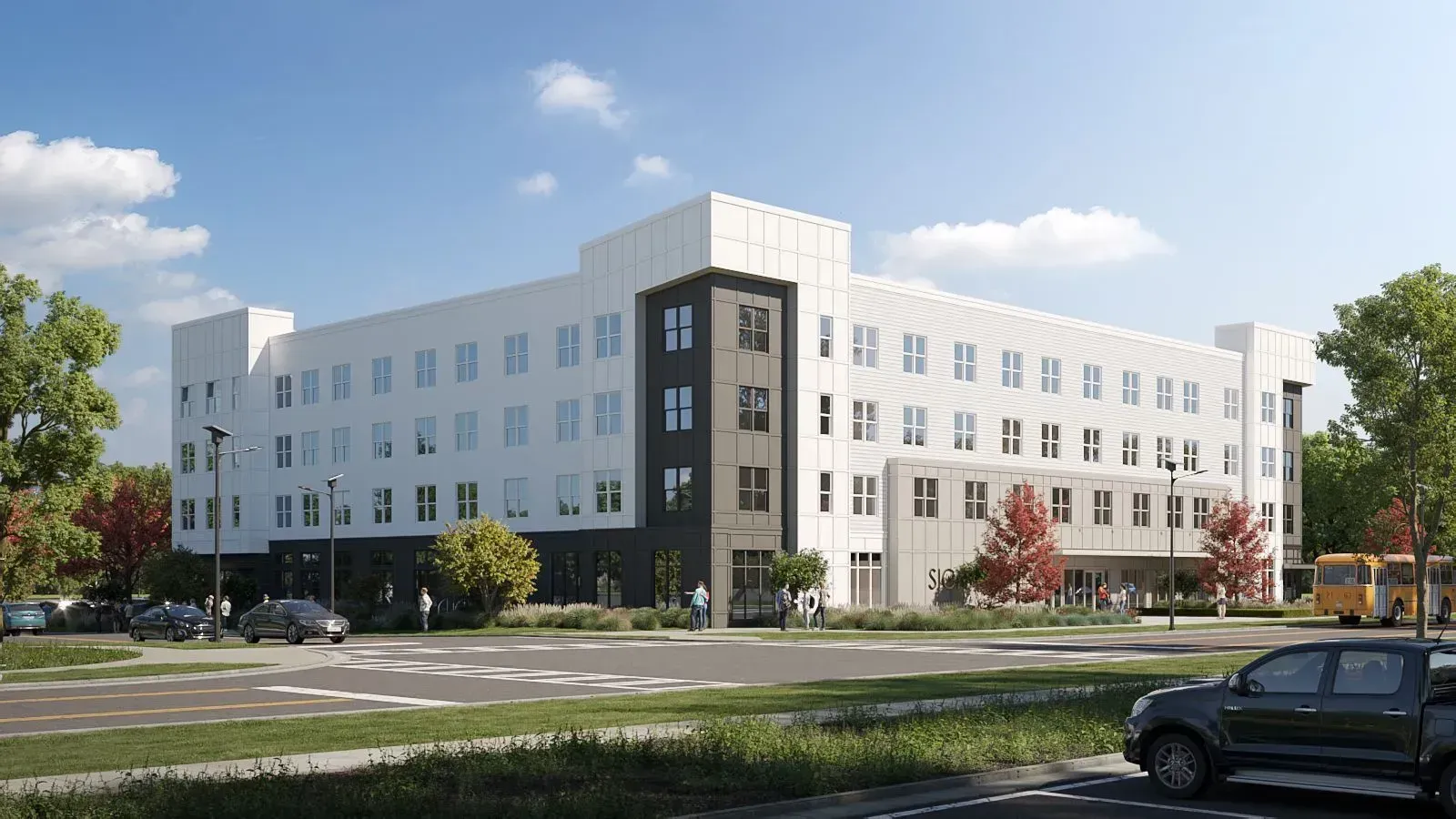 Exterior view of a modern white multi-story apartment building with landscaped entrance and street in foreground.
