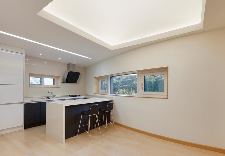 Bright modern kitchen with white cabinets, island seating, and large windows.