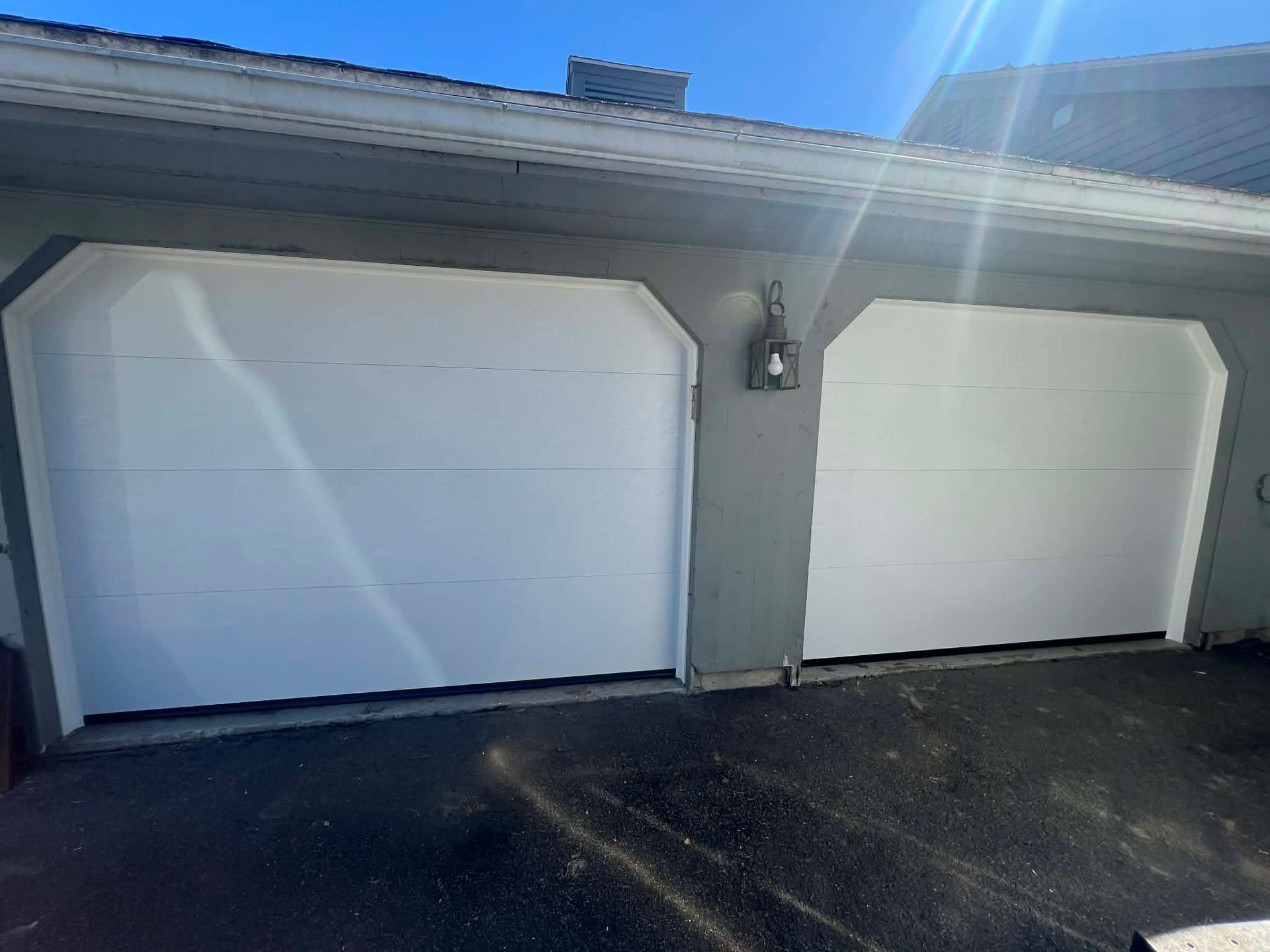 White garage doors on a gray building under a sunny sky.