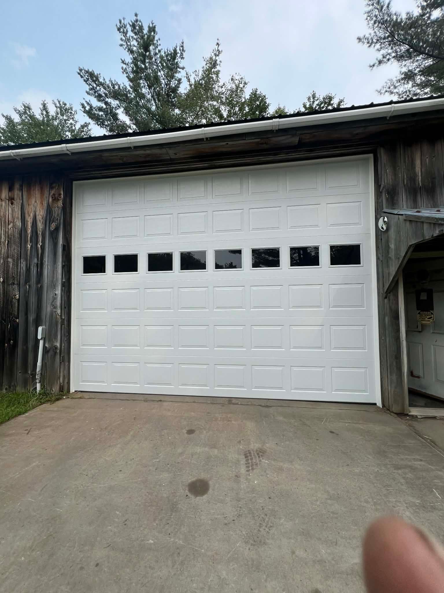 White garage door with rectangular windows on a weathered wooden building.
