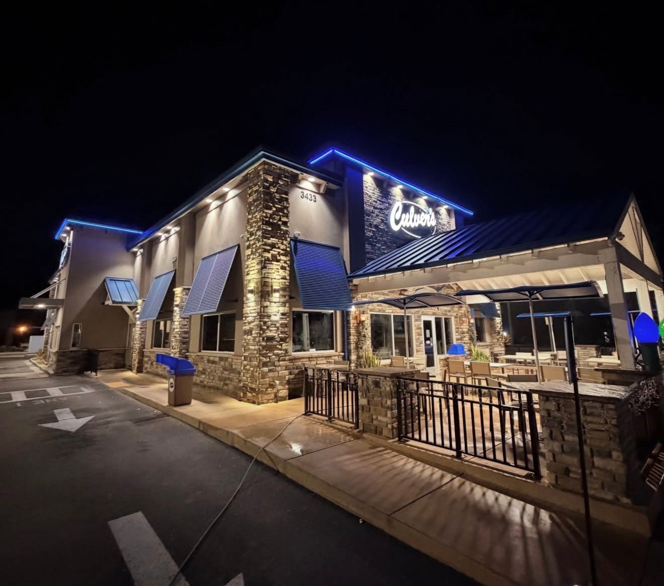 Modern building with red brick facade, large windows, and palm trees at entrance.