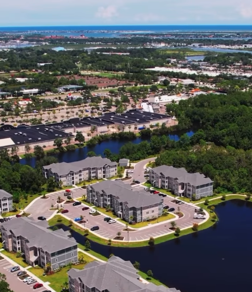 Aerial view of apartment buildings and a lake with commercial buildings in the background.