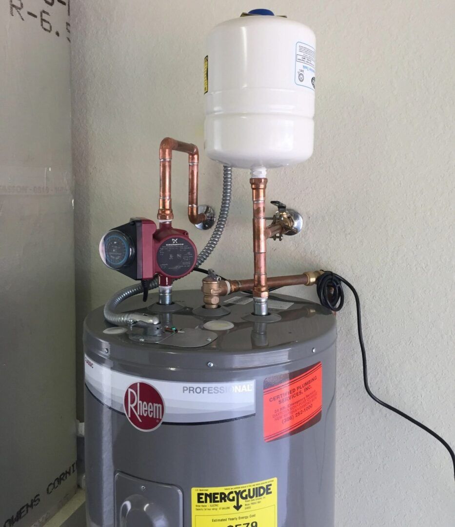 Water heater with a pump and expansion tank. Copper pipes connect components. Gray tank with red and yellow labels.