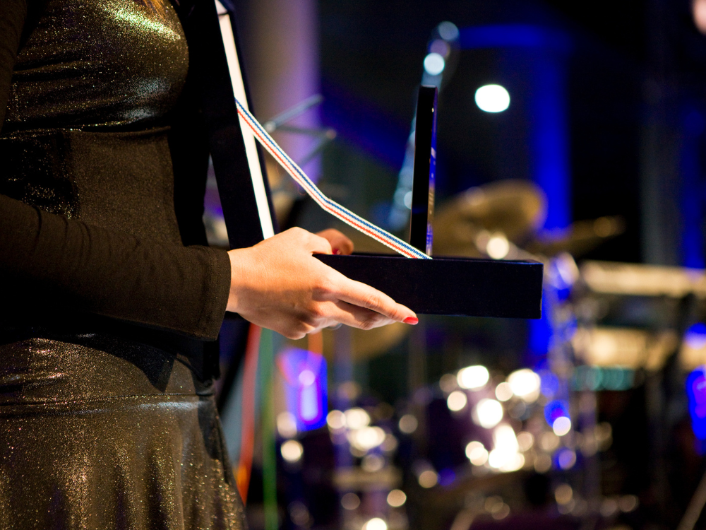 A woman in a black dress is holding a trophy