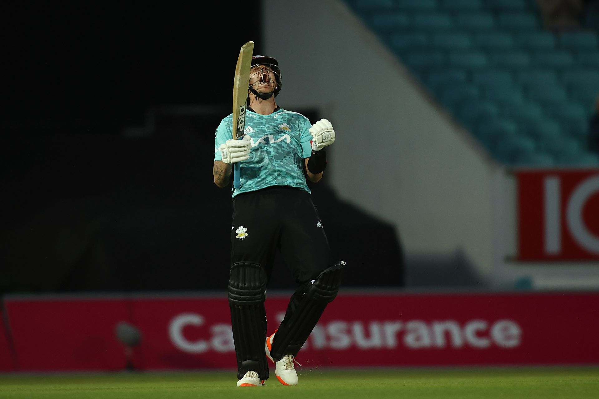 A man is holding a cricket bat on a field.